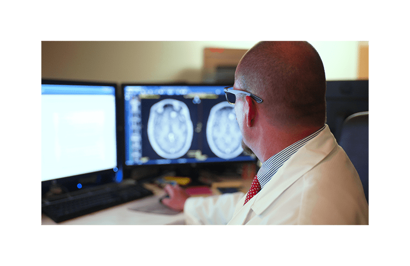 doctor looking at screen with brain scan visible