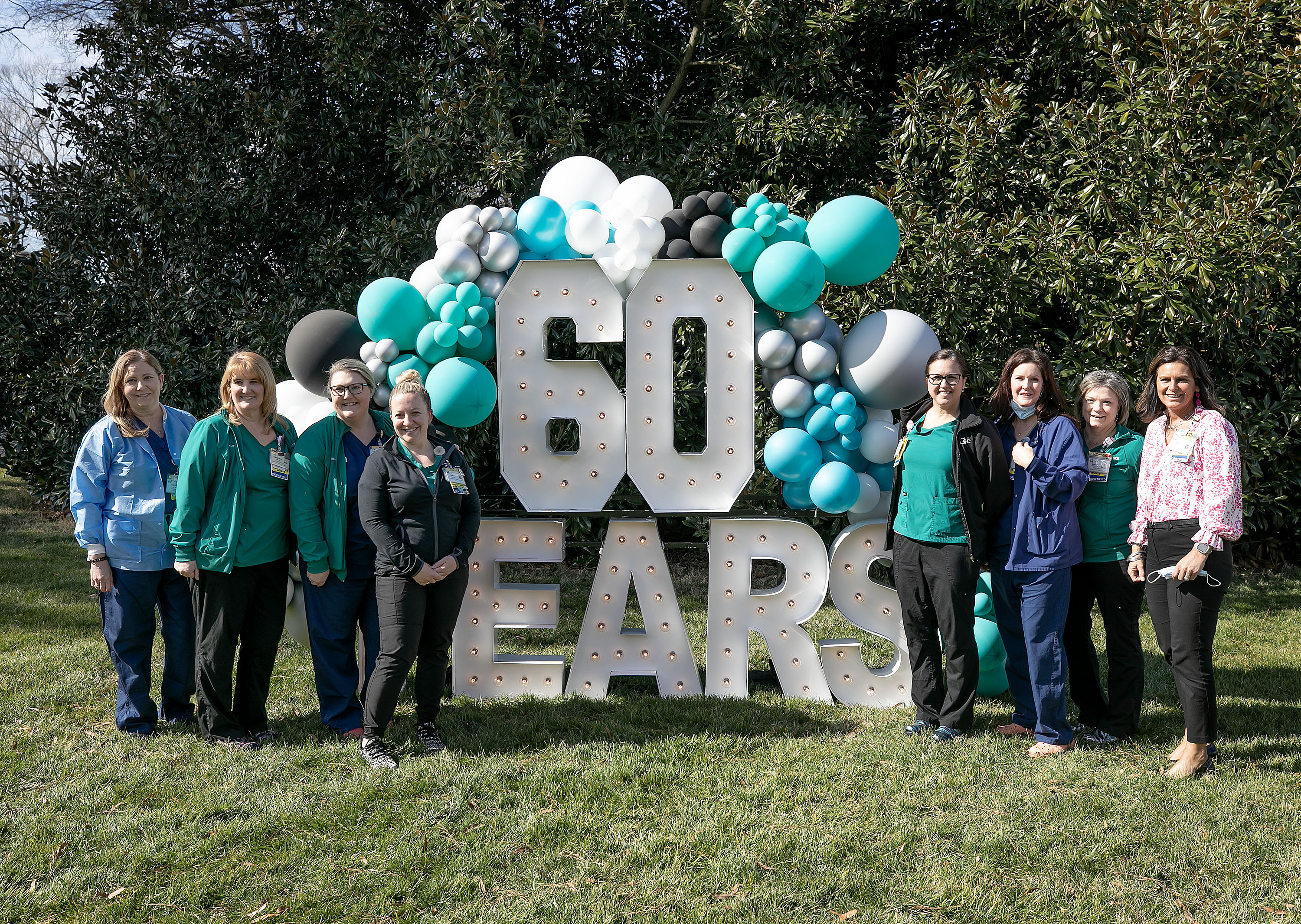 Group of nurses standing in front of sign that says 60 years