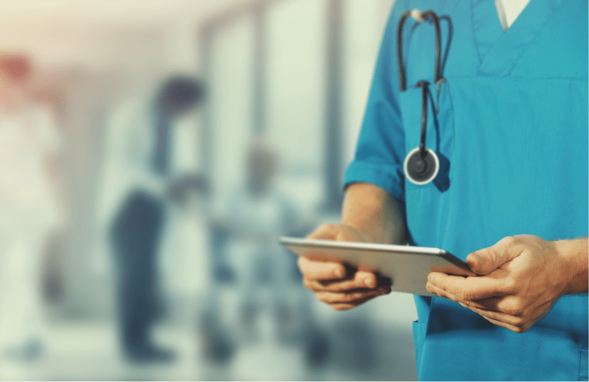 man holding a tablet in blue scrubs