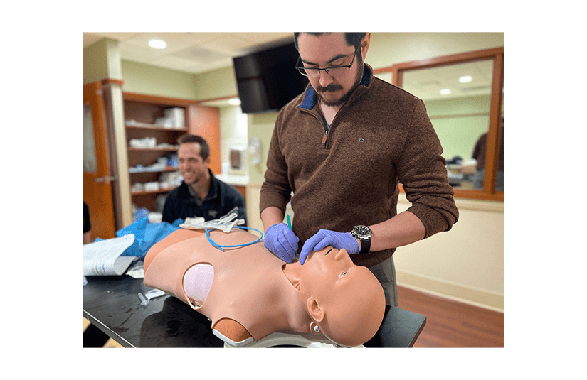 man standing over health simulation manikin 