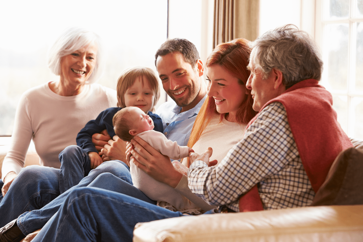 Care close to home, rooted where you are Multi Generation Family Sitting On Sofa With Newborn Baby Smiling
