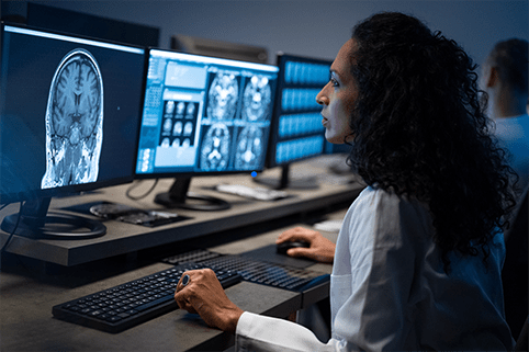 Side view of female radiologist looking at the MRI image of the head on her monitor and analyzing it.