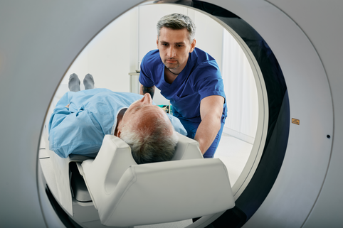 Screen for lung cancer with a Low Dose CT Scan Senior man going into CT scanner. CT scan technologist overlooking patient in Computed Tomography scanner during preparation for procedure