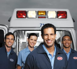 Portrait of a group of young paramedics posing behind an ambulance