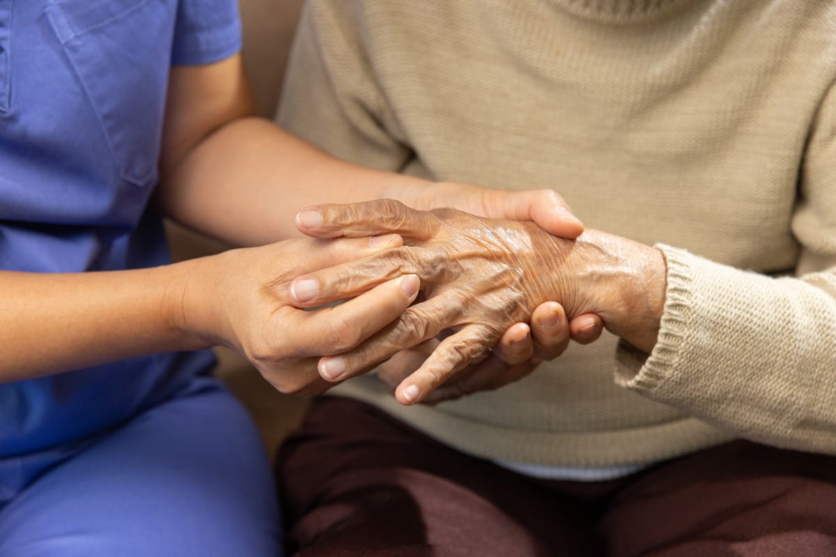 Nurse helping with patients hands