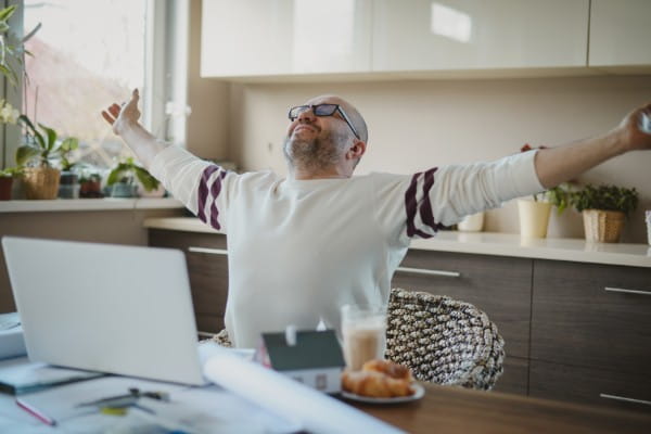 Mature adult man working at home stretching his arms